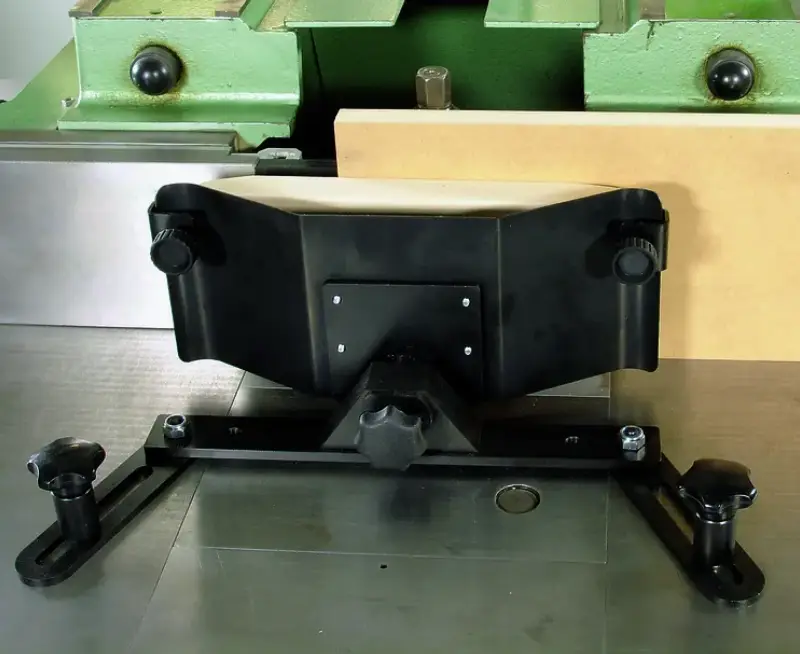 Nahaufnahme der Seitendruckvorrichtung Standard 14362: Schwarze Metallspannvorrichtung auf Werkbank, Maschine im Hintergrund.