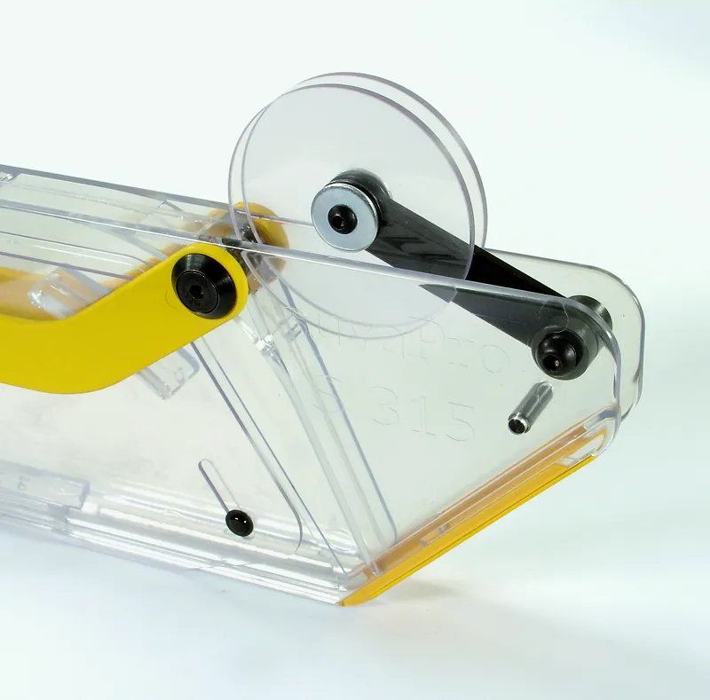Nahaufnahme eines transparenten Abrollers mit gelbem Griff, Ritzblattverdeckung zu Schutzhaube S 315 und sichtbarer Kleberolle.
