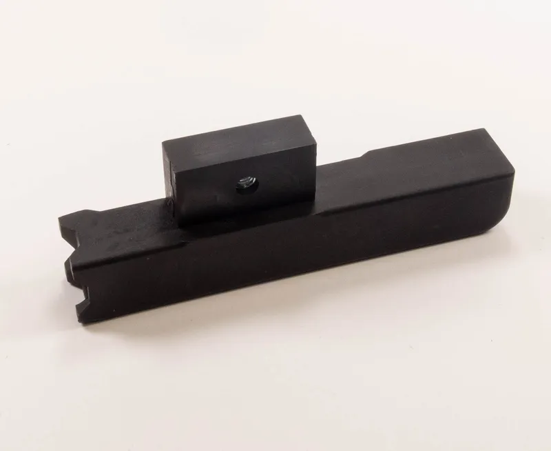 Der Druckschuh (317) aus schwarzem Metall mit rechteckigem Sockel, Block und Zentralschraube auf weissem Hintergrund.