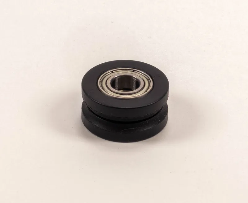 Schwarze Kunststoff-Metall-Laufrolle (Führung Messerwellenverdeckung) mit Kugellager, auf weissem Hintergrund.