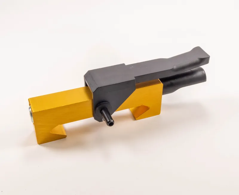 Mitnahmesystem 321: Gelb-schwarzes Werkzeugsicherheitssystem mit rechteckigem Sockel, zentraler Duese und zwei geneigten Traegern.