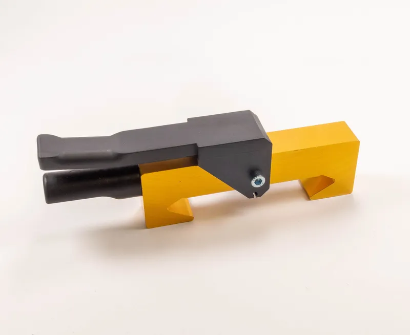 Das Mitnahmesystem 321 ist ein gelb-schwarzes Metall-Werkzeug mit rechteckiger Basis und zwei schwarzen Zylindergriffen.