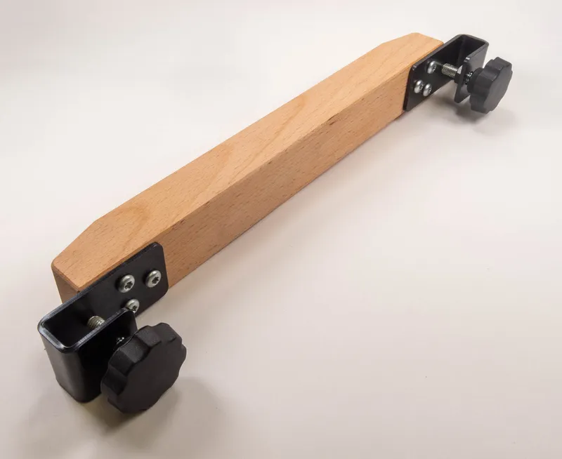 Hilfsholz mit schwarzen Metallbeschlägen und großen Kunststoffgriffen, Schutz- und Druckvorrichtung auf hellem Untergrund.