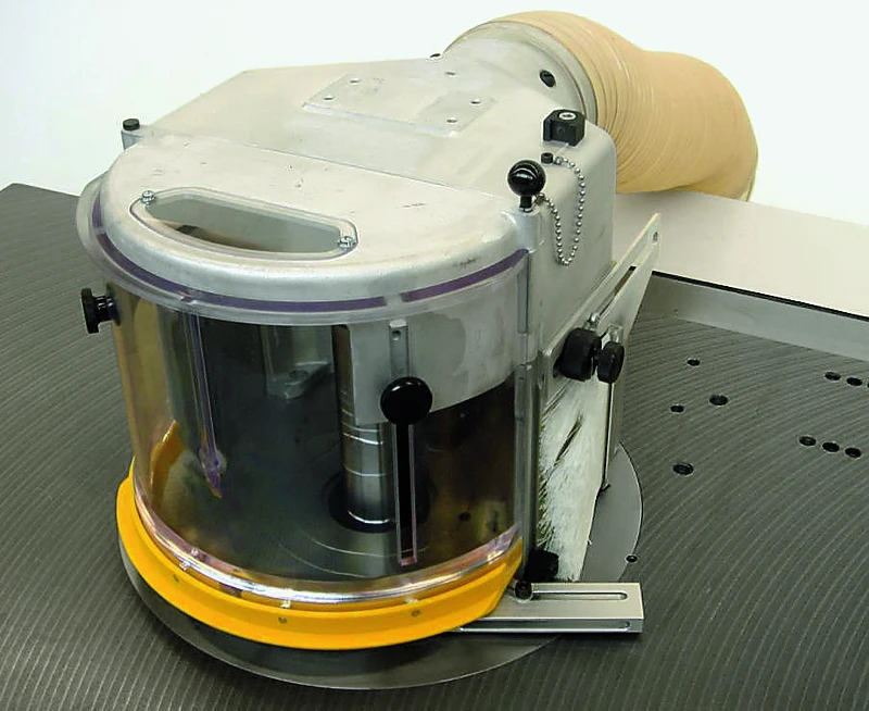 Nahaufnahme Bogenfraesschutz Modell T, Grundausführung, auf Werkbank mit Klarsichtschutz, Metallgehäuse, Absaugschlauch.