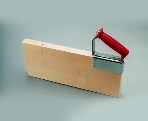 Handgriff hoch (9338), roter Metallgriff, an Holzbrett für hohe Schiebehölzer, Arbeitsschutz, auf grauem Grund befestigt.