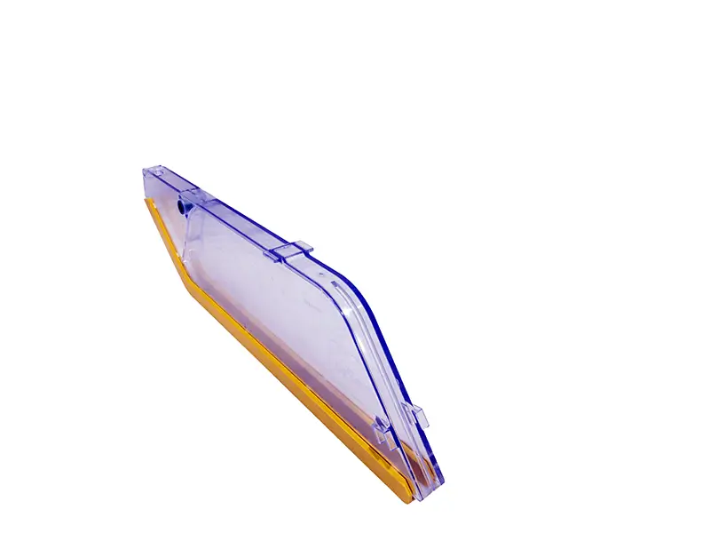 Transparenter Kunststoffdeckel mit gelbem Rand, schräg fotografiert. Schutzhaube B90 mit Schlitzen für Schienen, optimaler Arbeitsschutz.